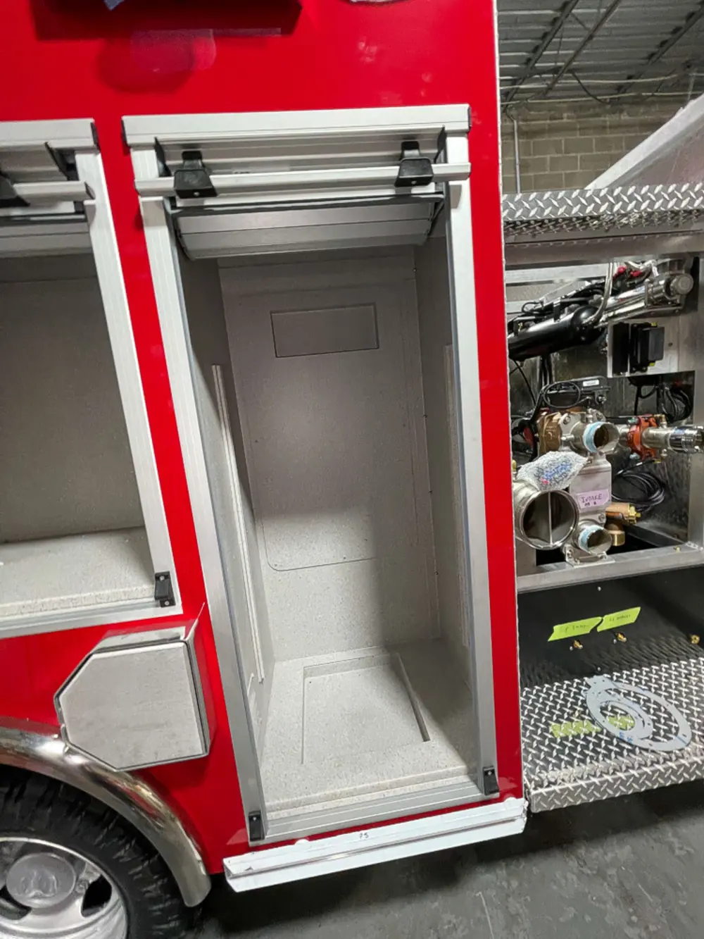Exterior view of small fire truck showing cab, body compartments, and wheel/tire area.